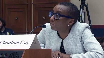 Claudine Gay in a white blazer sitting at a table.