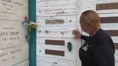 woman stands in front of defaced crypt