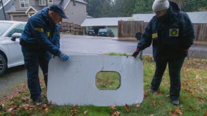 two officials holding up plane's door plug