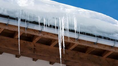 Long icicles and snow overhaning the roof and gutter of a building