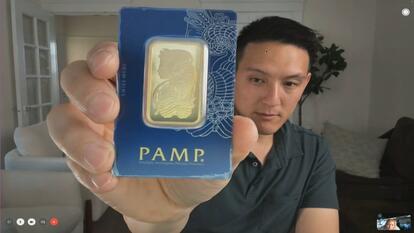 Person holding gold bar up to camera
