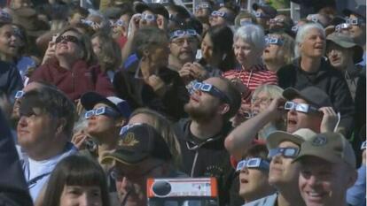 people looking at sky wearing solar eclipse glasses