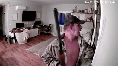 Man holding a weapon standing in a living room. 