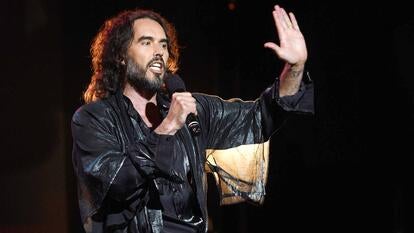 Russell Brand on stage speaking into a microphone