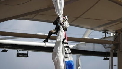 Man clinging to a parachute fabric as it hands from a metal roof