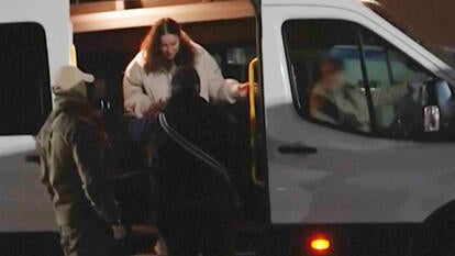 Woman being helped out of a white van by two men