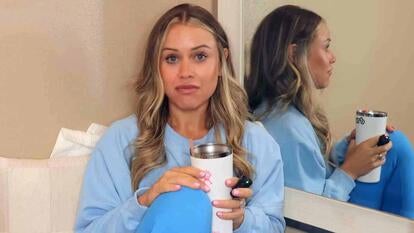 Woman sitting on a couch holding a tumbler with a drink inside