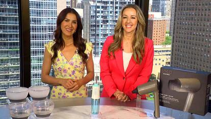 Two women behind a table displaying freezer bowls, a water flosser, and a hair dryer