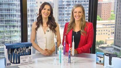 Two women behind a table displaying flatware, toothbrushes, and a scale