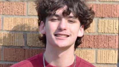 Teen smiling in front of a brick wall