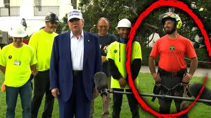 President Donald Trump standing on a lawn in front of people in bright colored shirts and hard hats, a red circle around a person on the far right