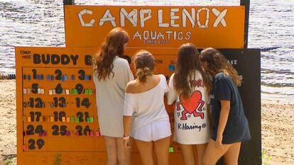 Four young girls standing in front of a sign reading 'Camp Lenox Aquatics'