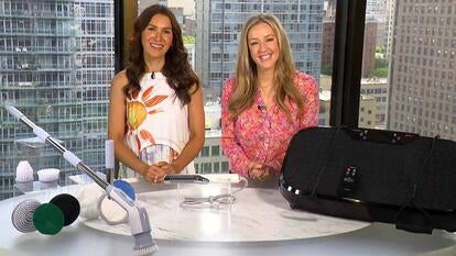 Two women standing behind a table displaying a hair straightener, a cleaning brush, and a Vita Trainer