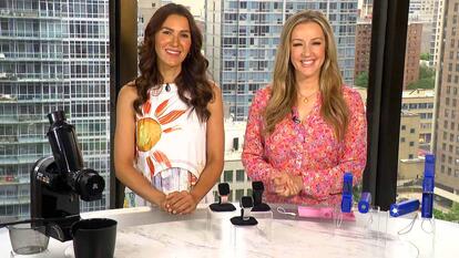 Two women stanidng behind a table displaying a juicer, smartwatch, and fan power bank