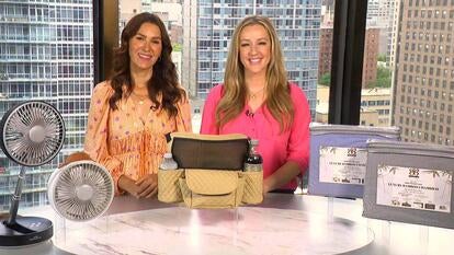 Two women standing behind a table displaying a fan, valet bags, and sheets