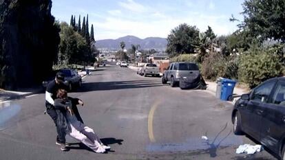 Surveillance image of a man pulling an unconscious woman out of the road