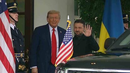President Donald Trump standing next to President Zelenskyy outside the White House with an American flag in the foreground