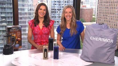 Two women behind a table displaying a cold brewer, air compressor, and air mattress