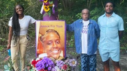 A family stands next to a memorial with a large sign reading 'Justice for Latoya'