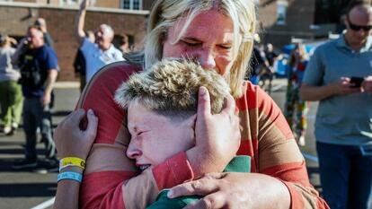 Mother and son hug each other while crying, in front of school