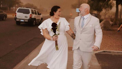 Newlywed couple standing in a sandstorm 