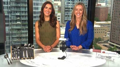 Two women behind a table displaying flatware, a dash cam, and a curling iron