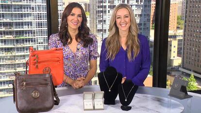 Two women standing behind a table displaying a Crossbody, Jewelry, Charging Stand