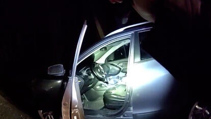 Police officer shines flashlight into car 