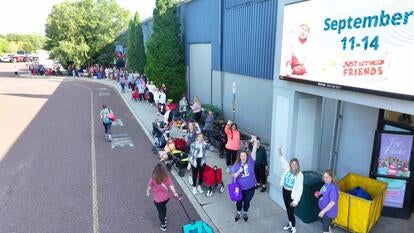 Long line of people standing in front of the doors to a warehouse 