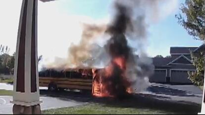 Home security camera footage of a school bus on fire on suburban street