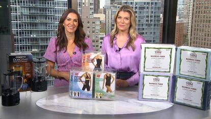 Two women standing behind a table displaying a Cold Brewer, Shapewear, Sheet Set