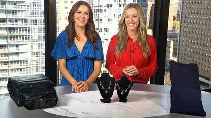 Two women standing behind a table displaying Air Mattress, Necklace, Thermal Set