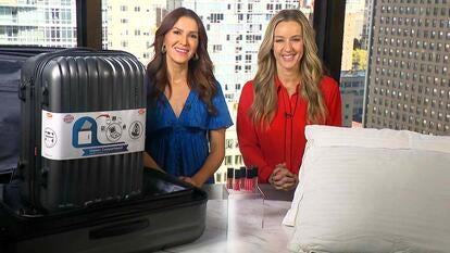 Two women behind a table displaying Luggage Set, Lip Oils, Pillows