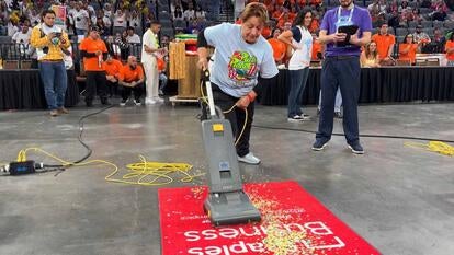 Woman pushing a vacuum over a red carpet