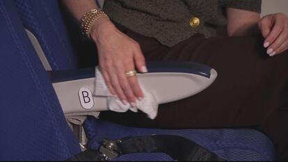 Woman's hand wiping down a plane seat arm rest