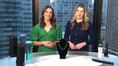 Two women standing behind a table displaying a Portable Blenders, Tennis Necklace, Cordless Vacuum