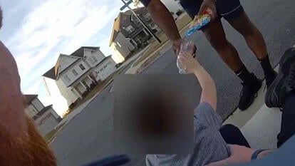 Little boy takes bottle of water from adult