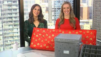 Two women standing behind a table displaying a Charging Stand, Screwdriver, Storage Boxes