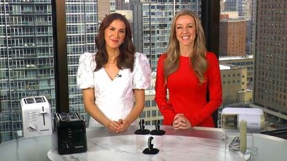 Two women standing behind a table displaying a Toaster, Tennis Bracelet, Handheld Vacuum