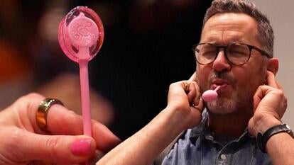 High-tech lollipop, man plugging ears with lollipop in mouth