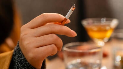 Young woman's hand holding a cigarette at a bar