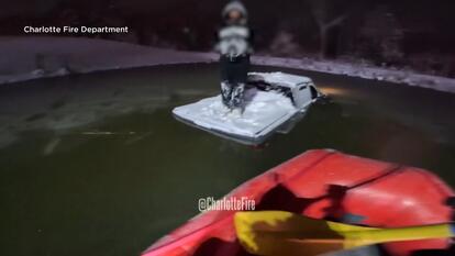 Man standing in the bed of his pickup truck in the middle of a pond.