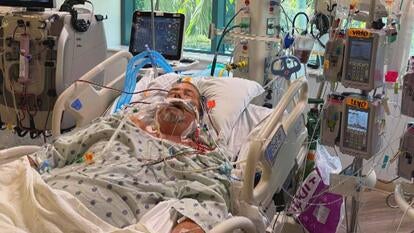 Unconscious man in a hospital bed surrounded by medical machines 