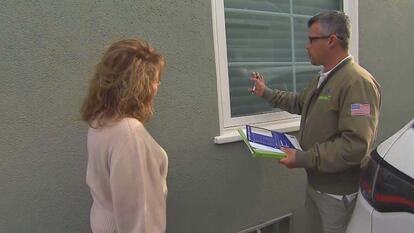 Woman watching as a home inspector points to an exterior window of a house