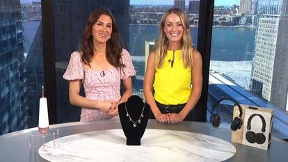 Two women standing behind a table displaying a Water Flosser, Necklace, Headphones