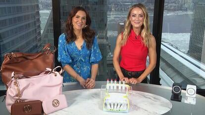 Two women behind a table displaying a Bag, Lip Balm, Charging Station
