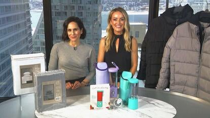 Two women behind a table displaying a Sheet Set, Portable Blender, Puffer Jacket
