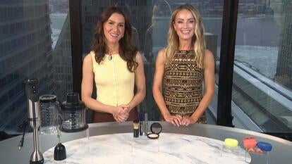 Two women standing behind a table displaying a Blender Bundle, Makeup Set, Wireless Earbuds