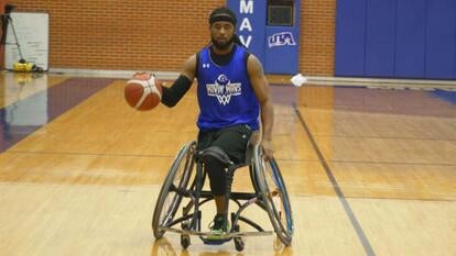 Michael Collins dribbling a basketball down a basketball court while in a wheelchair