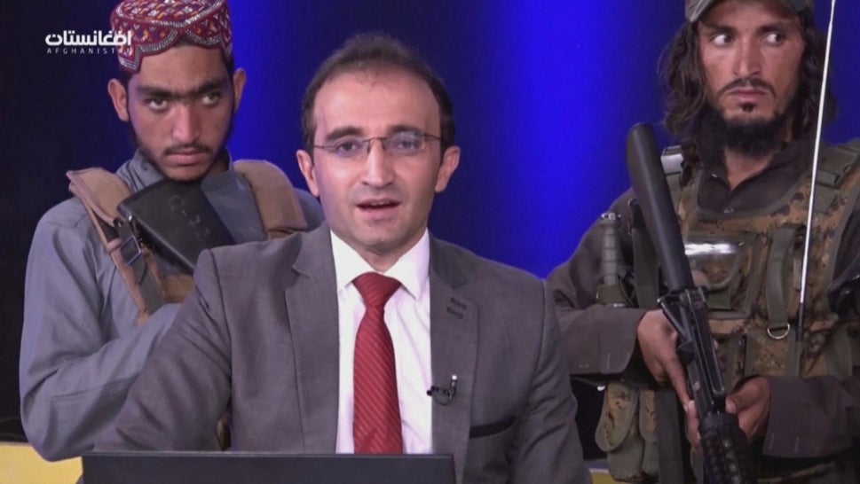 A news anchor surrounded by armed Taliban members